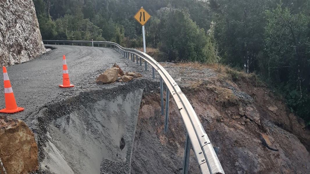 A road has slipped away as it winds around a steep, cliff section.