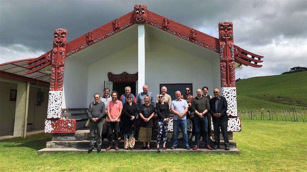 13 people stand in front of a marae