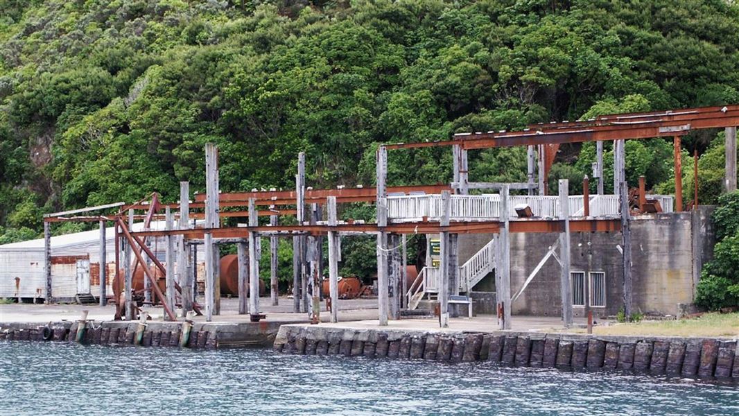 Rusting metal remains on a wharf as seen from a boat.