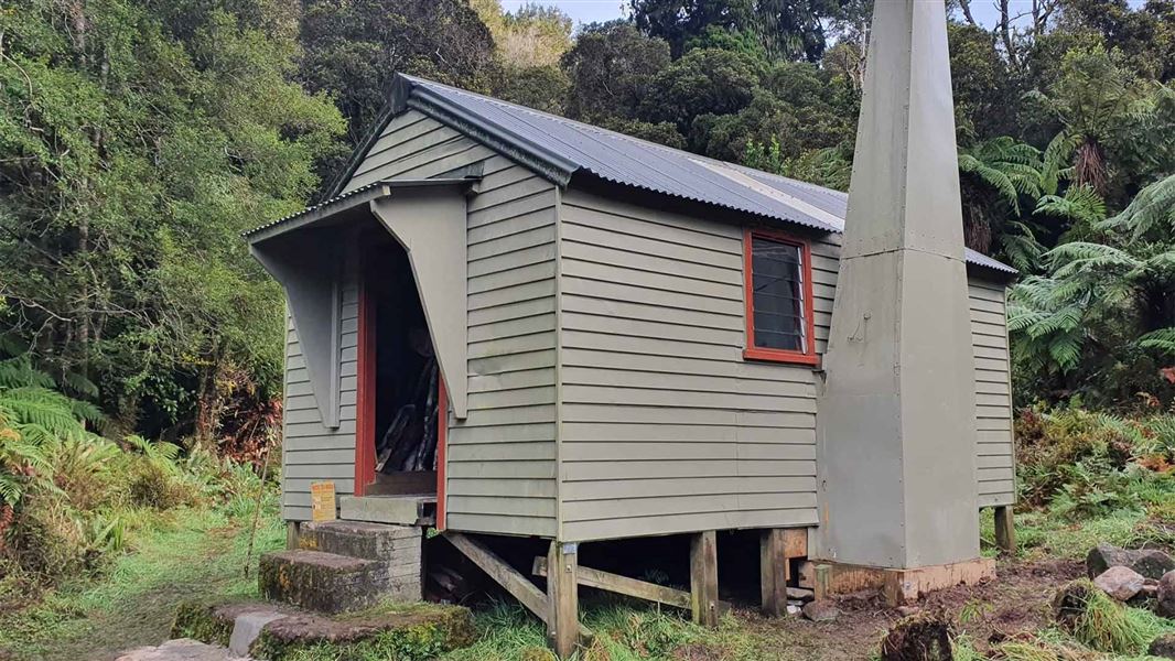 A small metal hut in some dense forest.