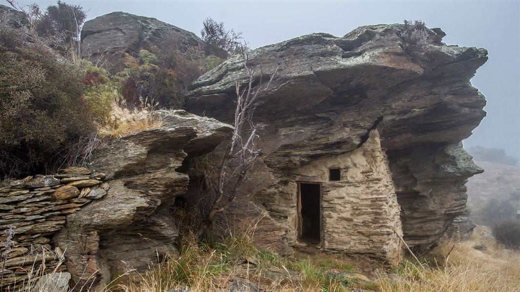 A stone shack built into the side of a cliff.