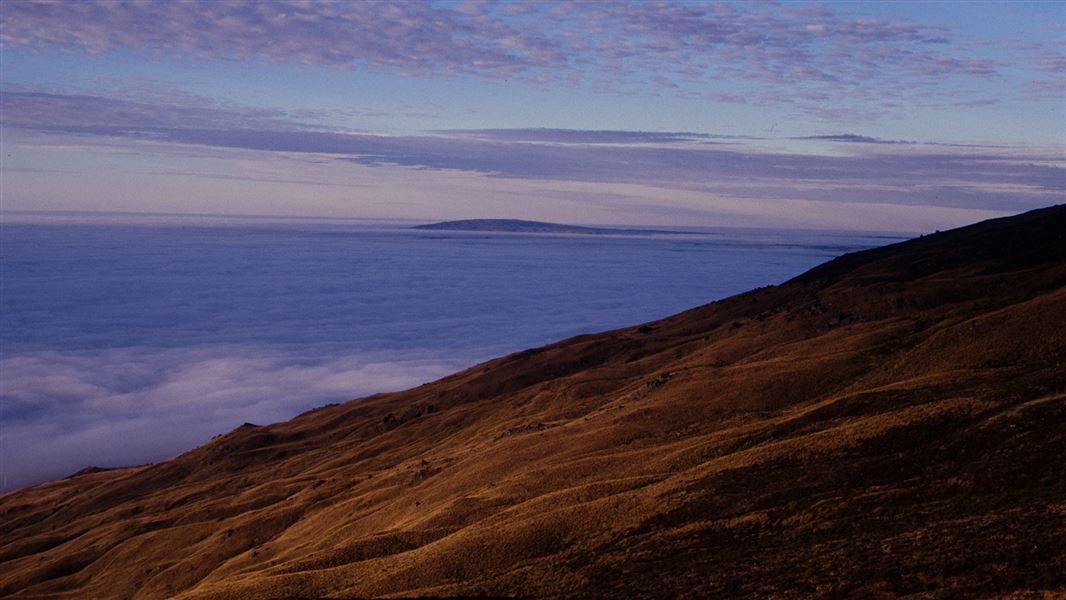 View from the side of a range across low-lying cloud to a distant range.