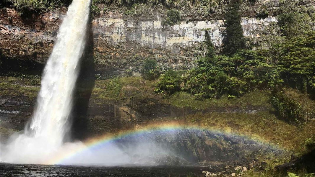 A large waterfall smashes into a small lake.